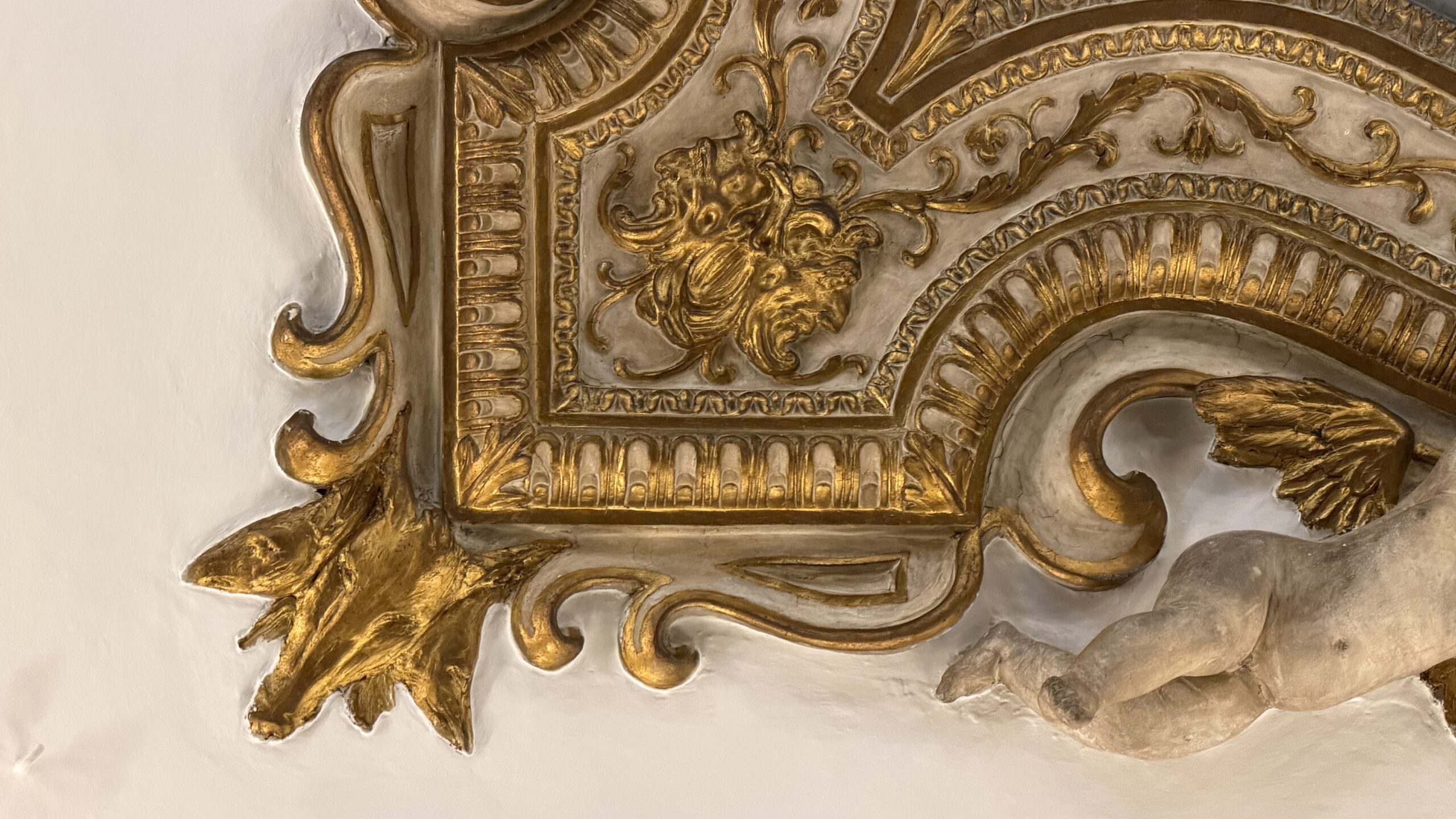 Angolo della cornice in stucco dorato con un putto disteso