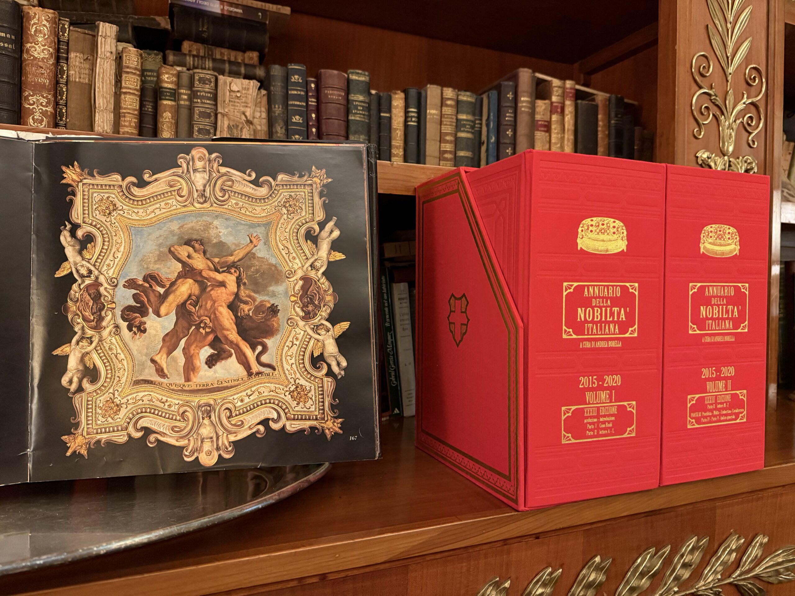 Il libro aperto sull'affresco, accanto ai volumi rilegati della biblioteca